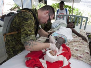 Le caporal Alex Robitaille soigne une jeune fille à l'hôpital de Jacmel. Le caporal Alex Robitaille soigne une jeune fille à l'hôpital de Jacmel.