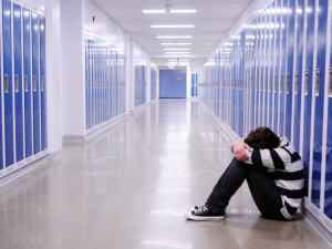 Jeune homme assis dans un couloir d'école Jeune homme assis dans un couloir d'école