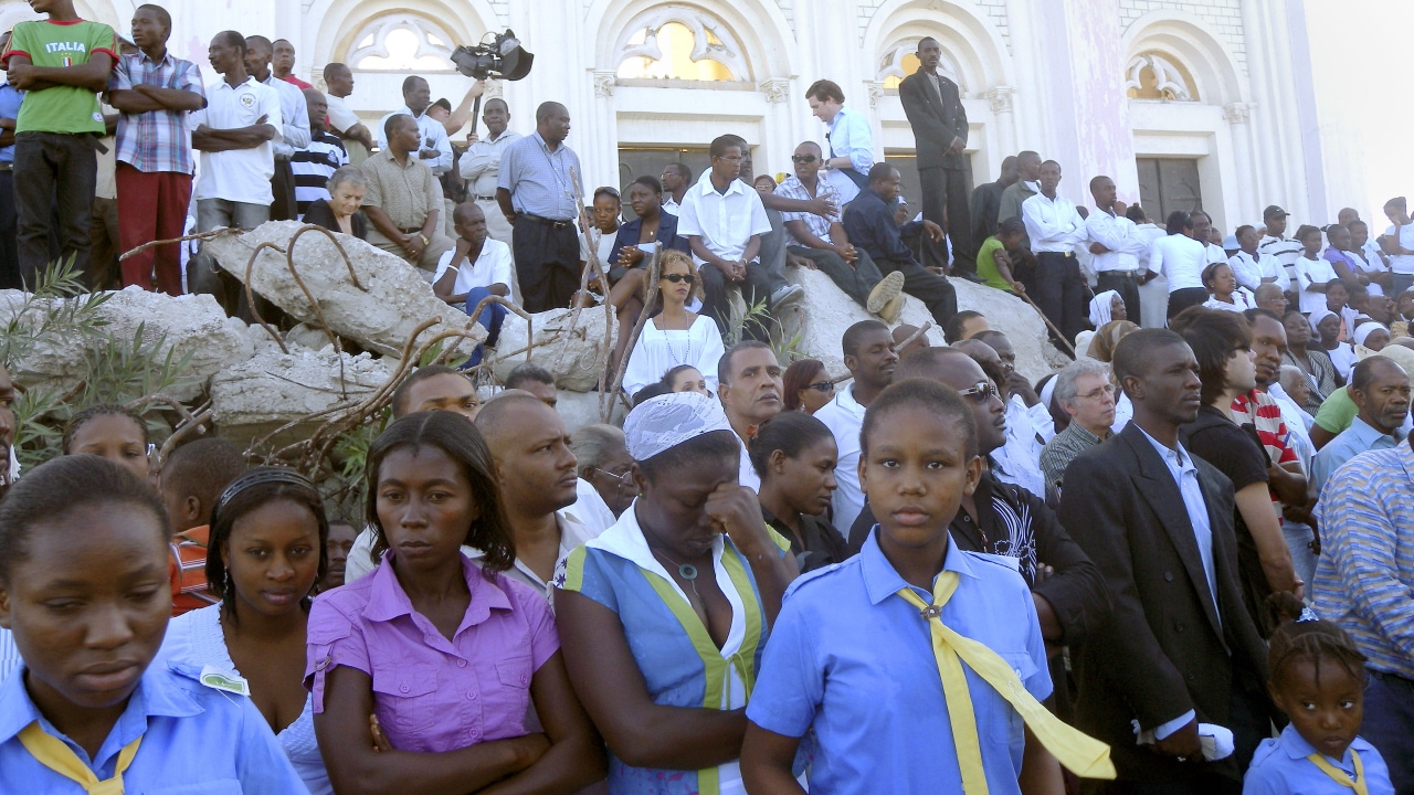 Des Haïtiens prient au pied de la cathédrale Notre-Dame, à Port-au-Prince. Des Haïtiens prient au pied de la cathédrale Notre-Dame, à Port-au-Prince.