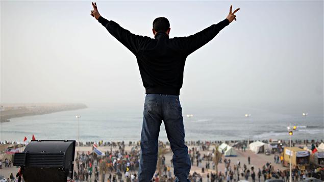 À Benghazi, un homme juché sur le toit du palais de justice, où le gouvernement de transition a élu domicile, fait le signe de la victoire. La place publique située sur le bord de la plage est devenue le point de rassemblement des insurgés. À Benghazi, un homme juché sur le toit du palais de justice, où le gouvernement de transition a élu domicile, fait le signe de la victoire. La place publique située sur le bord de la plage est devenue le point de rassemblement des insurgés.