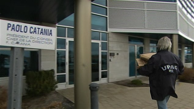 Un enquêteur de l'UPAC transporte des boîtes de carton sur les lieux de la perquisition. Un enquêteur de l'UPAC transporte des boîtes de carton sur les lieux de la perquisition.