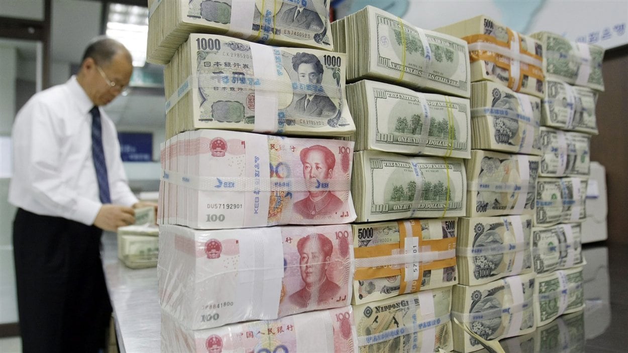 Un employé d’une banque en Corée du Sud près d’une pile de billets en devises étrangères (archives). Un employé d’une banque en Corée du Sud près d’une pile de billets en devises étrangères (archives).