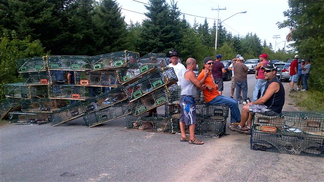 Les manifestants ont barré l'accès à l'usine Village Bay avec leurs cages de homards à Bedec, au Nouveau-Brunswick. Les manifestants ont barré l'accès à l'usine Village Bay avec leurs cages de homards à Bedec, au Nouveau-Brunswick.