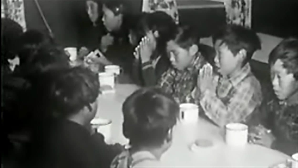 Des élèves d'un pensionnat autochtone au Canada font une prière avant leur repas. Des élèves d'un pensionnat autochtone au Canada font une prière avant leur repas.