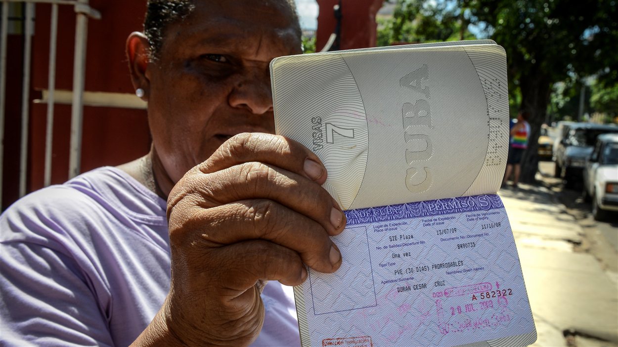 Une Cubaine montre sa carte blanche, un permis de sortie du pays dont les citoyens n'ont désormais plus besoin pour sortir du pays Une Cubaine montre sa carte blanche, un permis de sortie du pays dont les citoyens n'ont désormais plus besoin pour sortir du pays