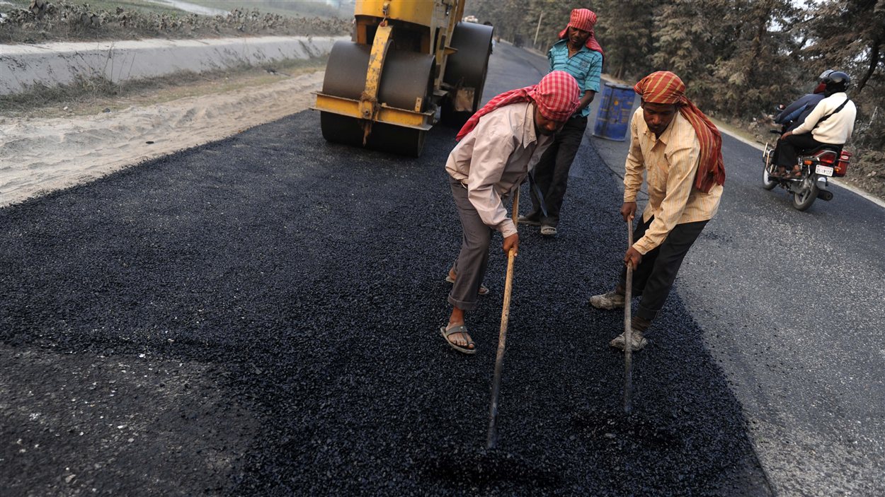 Des travailleurs indiens asphaltent une route. Des travailleurs indiens asphaltent une route.