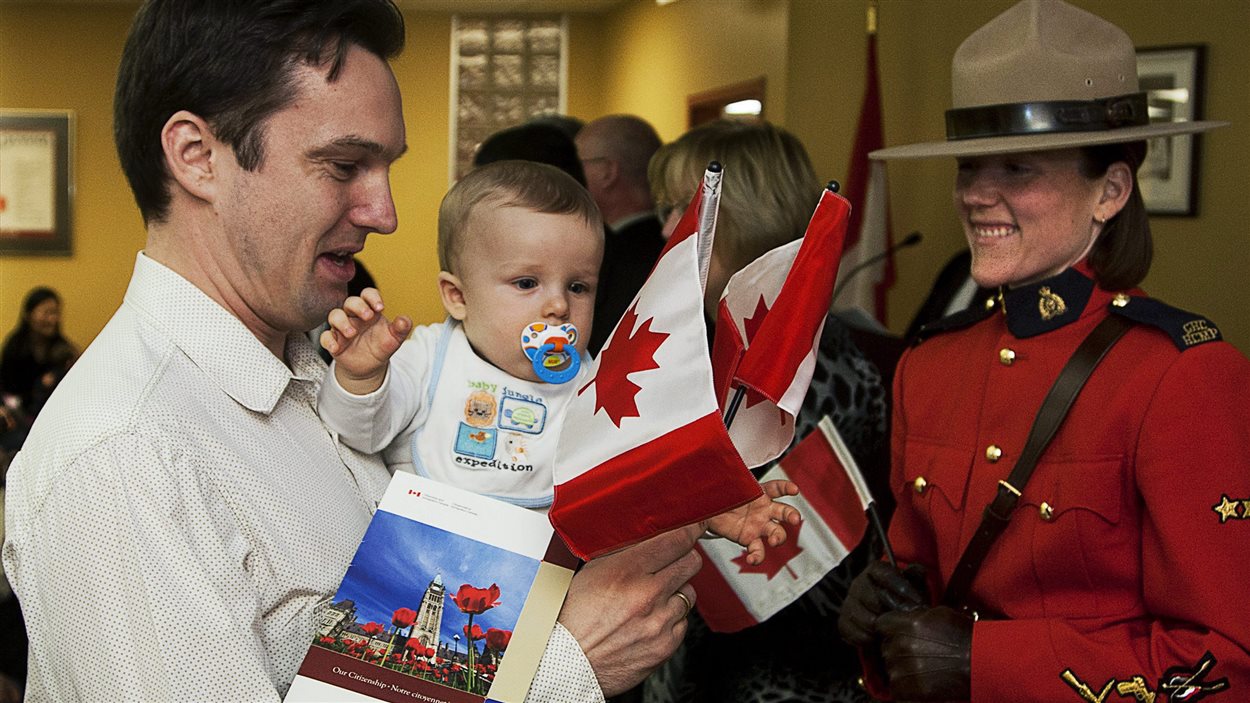 La constable Meredith Darrah regarde Michael Kopec, originaire de la Slovaquie, qui prend part avec son fils Max à une cérémonie de citoyenneté, à Halifax, le 15 février 2011. La constable Meredith Darrah regarde Michael Kopec, originaire de la Slovaquie, qui prend part avec son fils Max à une cérémonie de citoyenneté, à Halifax, le 15 février 2011.