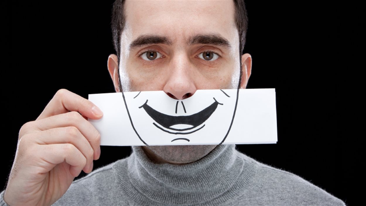 Un homme cache ses émotions derrière le dessin d'un sourire Un homme cache ses émotions derrière le dessin d'un sourire