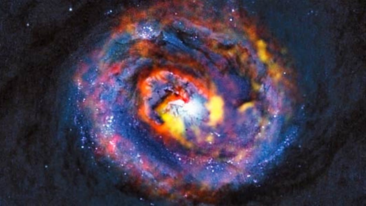 Cette vue détaillée montre les régions centrales de la galaxie active proche NGC 1433. L'image du fond, de couleur bleue sombre, a été obtenue par Hubble. Elle montre l'existence de bandes de poussière au centre de la galaxie. Les structures colorées situées à proximité du centre apparaissent sur les observations d'ALMA qui ont révélé, pour la toute première fois, l'existence d'une forme spirale et d'un écoulement inattendu. Cette vue détaillée montre les régions centrales de la galaxie active proche NGC 1433. L'image du fond, de couleur bleue sombre, a été obtenue par Hubble. Elle montre l'existence de bandes de poussière au centre de la galaxie. Les structures colorées situées à proximité du centre apparaissent sur les observations d'ALMA qui ont révélé, pour la toute première fois, l'existence d'une forme spirale et d'un écoulement inattendu.