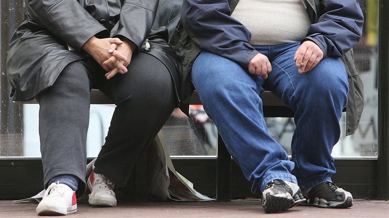 Un homme et une femme souffrant d'obésité attendent dans un abri d'autobus. Un homme et une femme souffrant d'obésité attendent dans un abri d'autobus.