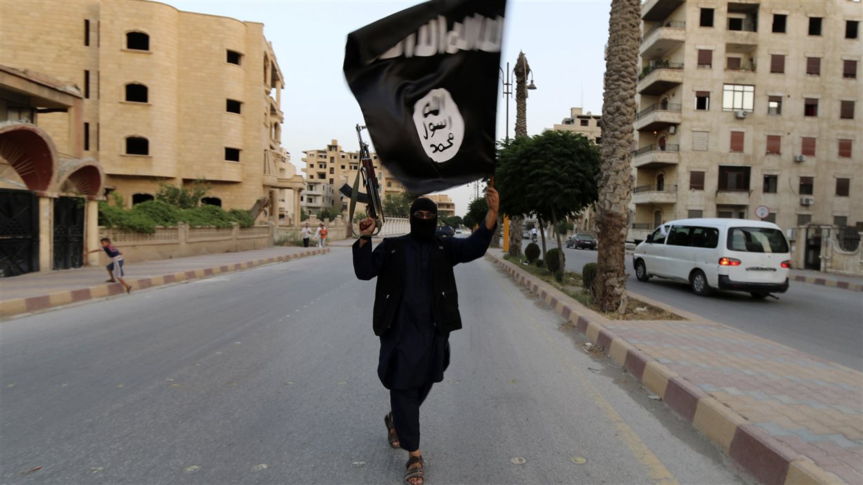 Un militant de l'État islamique brandit un drapeau du «califat» dans la ville syrienne de Saqqa. Un militant de l'État islamique brandit un drapeau du «califat» dans la ville syrienne de Saqqa.