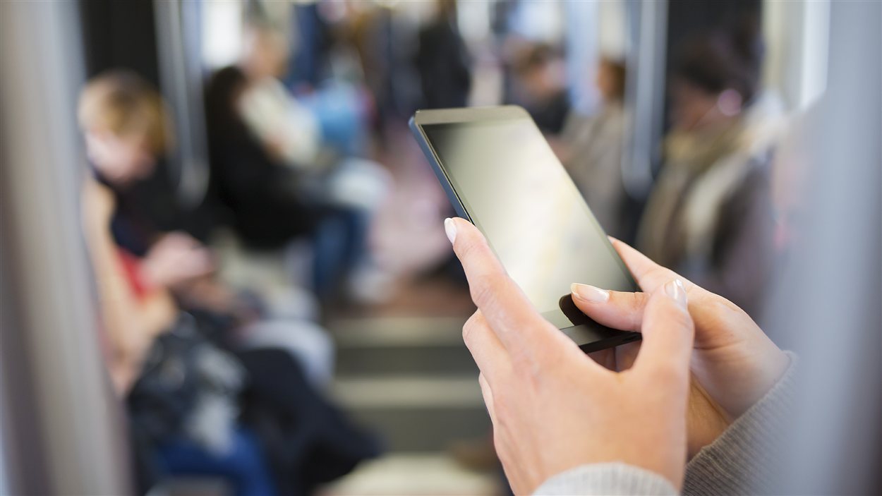 Une femme consulte son téléphone intelligent dans le métro Une femme consulte son téléphone intelligent dans le métro