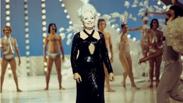 Dans un studio de télévision en 1972, la chanteuse Muriel Millard entourée d'une troupe de danseurs. Dans un studio de télévision en 1972, la chanteuse Muriel Millard entourée d'une troupe de danseurs.