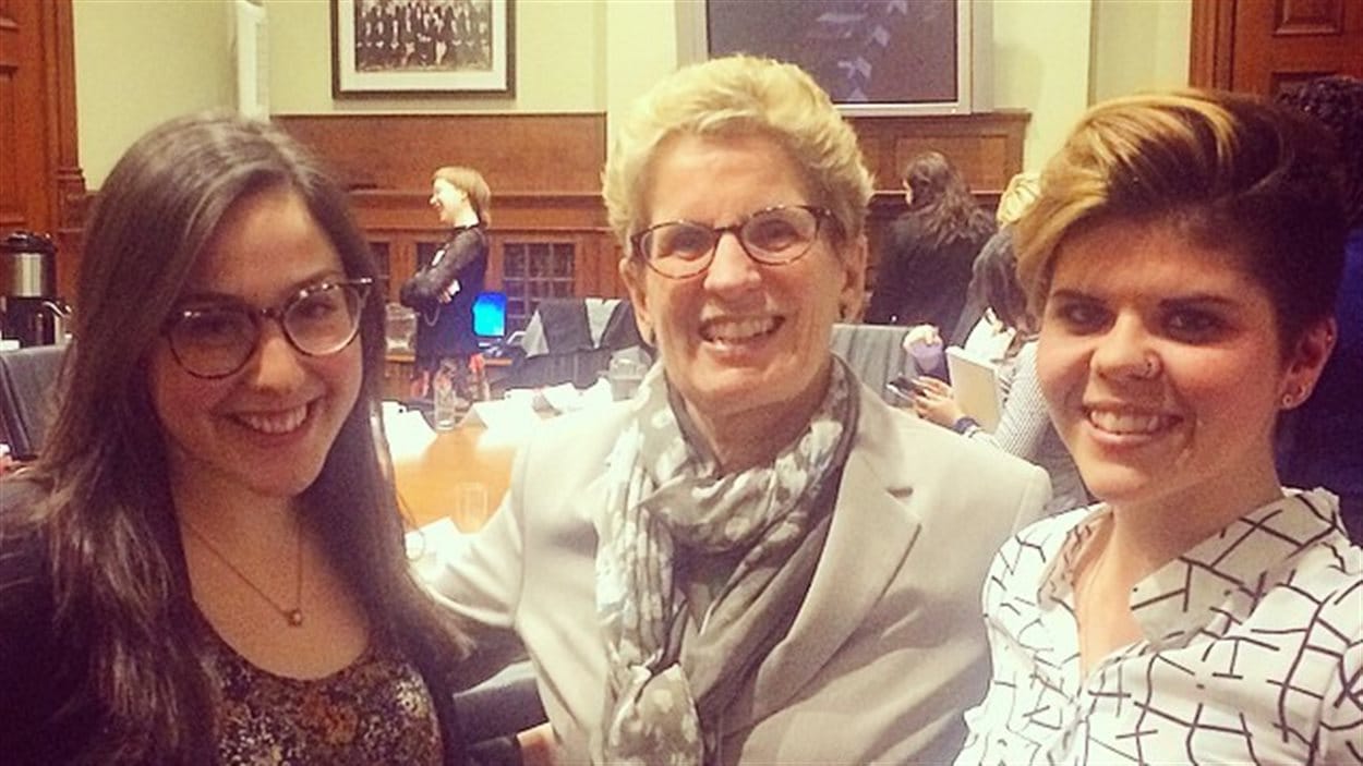 La première ministre Kathleen Wynne en compagnie de deux étudiantes de la Fédération canadienne des étudiants, dont Anna Goldfinch La première ministre Kathleen Wynne en compagnie de deux étudiantes de la Fédération canadienne des étudiants, dont Anna Goldfinch