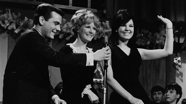 L'animateur Pierre Lalonde tient le micro devant les chanteuses Petula Clark et Michèle Richard, en 1966. L'animateur Pierre Lalonde tient le micro devant les chanteuses Petula Clark et Michèle Richard, en 1966.