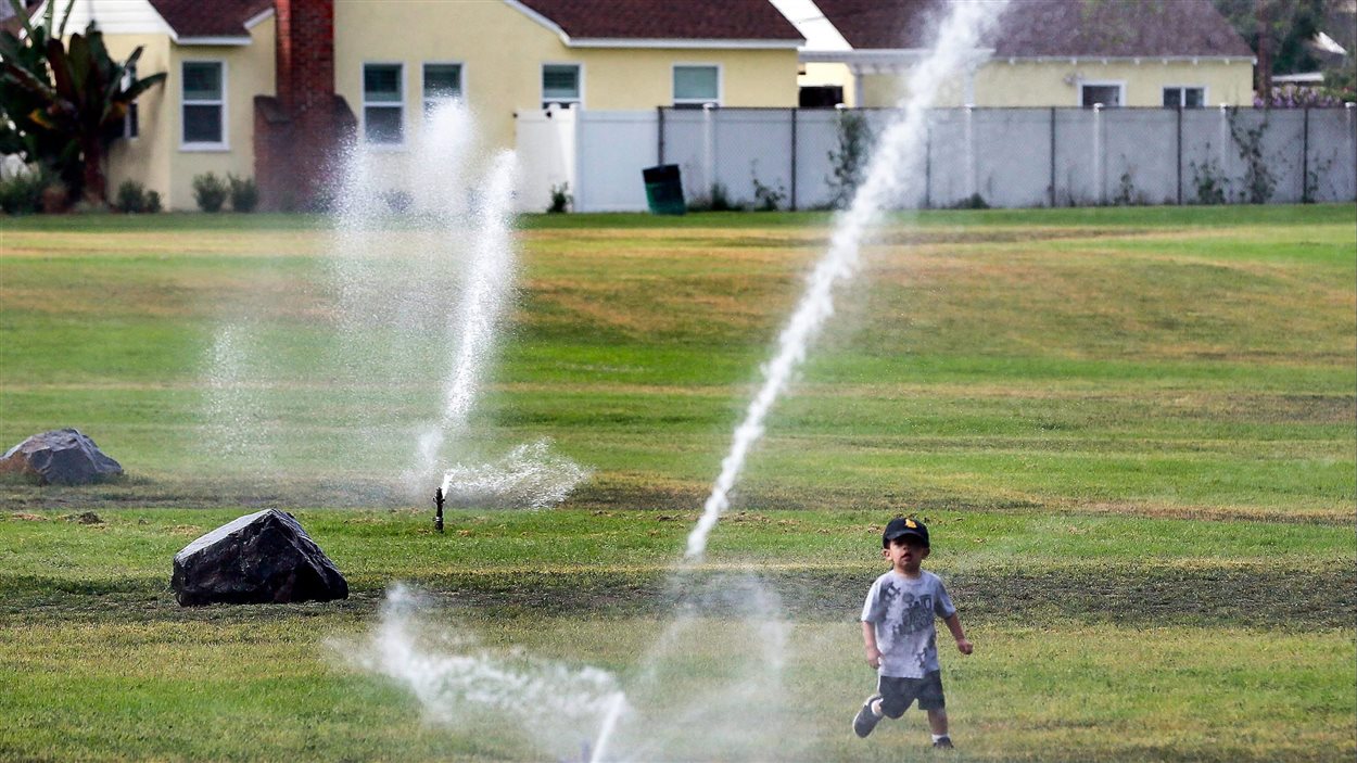 Un jeune garçon s'amuse parmi les gicleurs sur un terrain de Long Beach, en Californie. Un jeune garçon s'amuse parmi les gicleurs sur un terrain de Long Beach, en Californie.