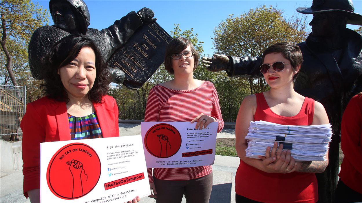 Trois femmes soutenant la campagne de Canadian Menstruators devant la statue de Célèbres cinq, sur la colline Parlementaire. Trois femmes soutenant la campagne de Canadian Menstruators devant la statue de Célèbres cinq, sur la colline Parlementaire.