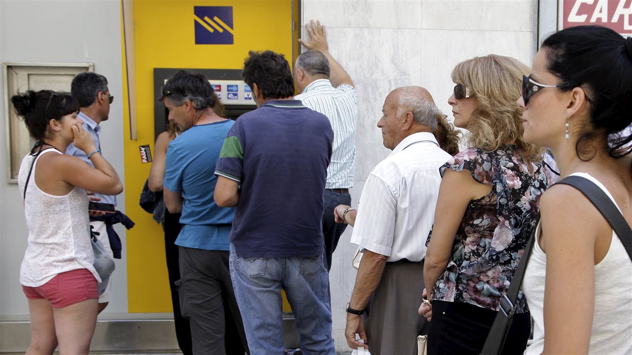 Des personnes font la file pour retirer de l'argent d'un guichet automatique devant une banque de l'île de Crète. Des personnes font la file pour retirer de l'argent d'un guichet automatique devant une banque de l'île de Crète.