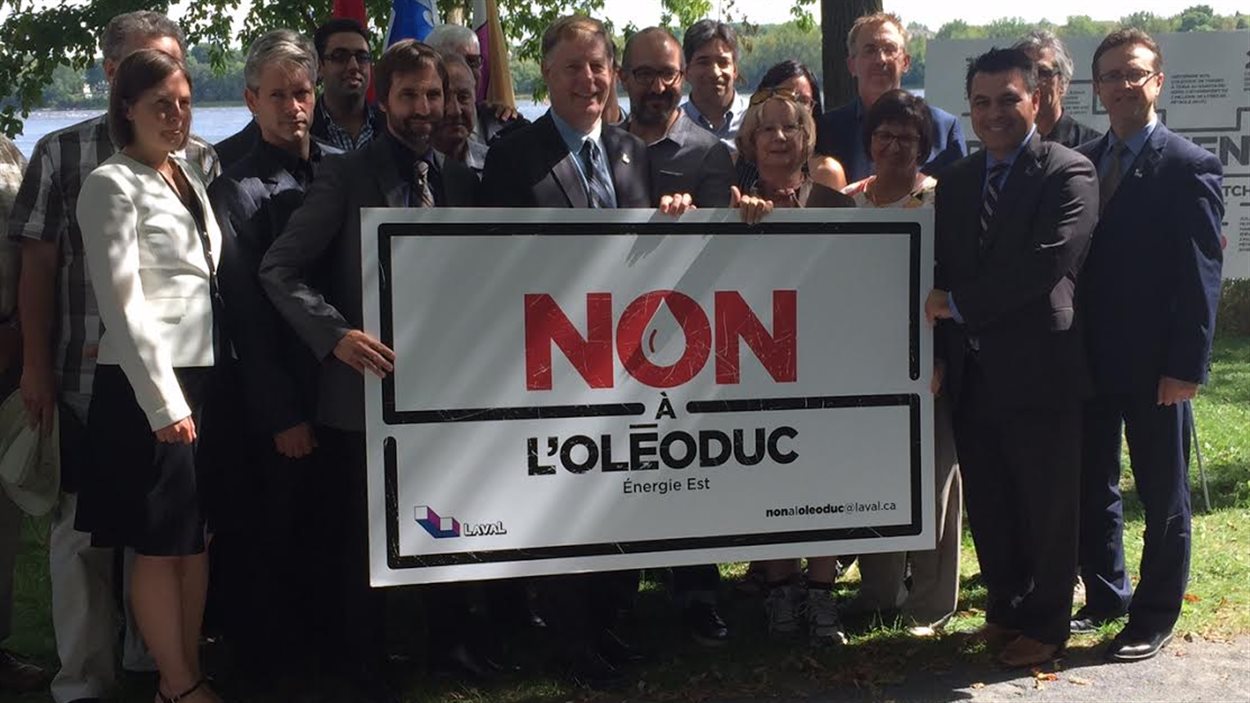 Le maire de Laval, entouré de citoyens et d'environnementalistes, dit non au projet Energie Est. Le maire de Laval, entouré de citoyens et d'environnementalistes, dit non au projet Energie Est.