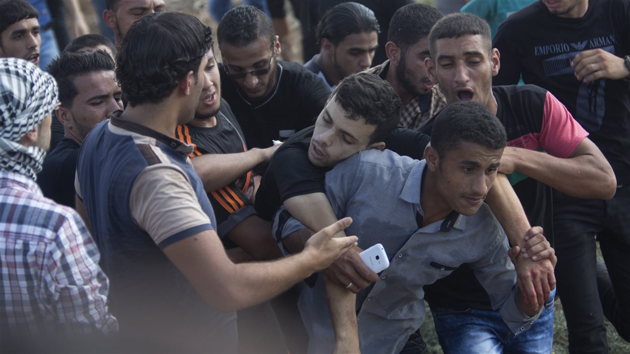 Des Palestiniens transportent un blessé à la suite de heurts avec des soldats israéliens à la frontière entre la bande de Gaza et Israël. Des Palestiniens transportent un blessé à la suite de heurts avec des soldats israéliens à la frontière entre la bande de Gaza et Israël.