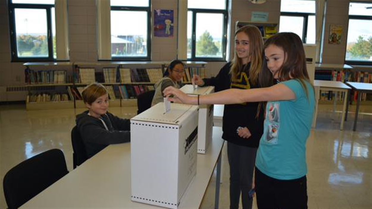 Des élèves de l’école secondaire des pionniers à Saint-Augustin-des-Desmaures, au Québec, déposent leur bulletin de vote. Des élèves de l’école secondaire des pionniers à Saint-Augustin-des-Desmaures, au Québec, déposent leur bulletin de vote.