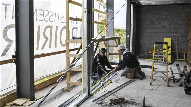 Les ouvriers utilisent des passerelles fixées à l'édifice plutôt qu'un échafaudage. Les ouvriers utilisent des passerelles fixées à l'édifice plutôt qu'un échafaudage.