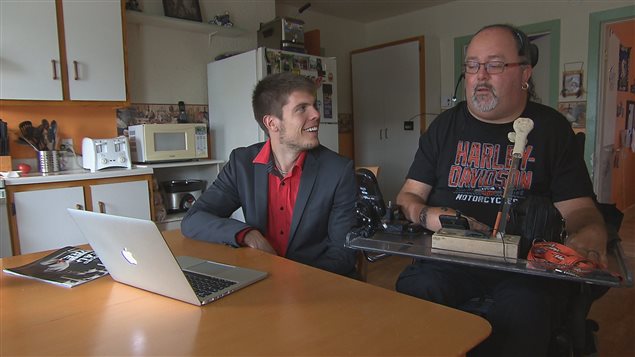 Samuel Fleurent-Beauchemin et Dany Martel regardent le bras JACO 3 doigts en action sur l'ordinateur portable Samuel Fleurent-Beauchemin et Dany Martel regardent le bras JACO 3 doigts en action sur l'ordinateur portable