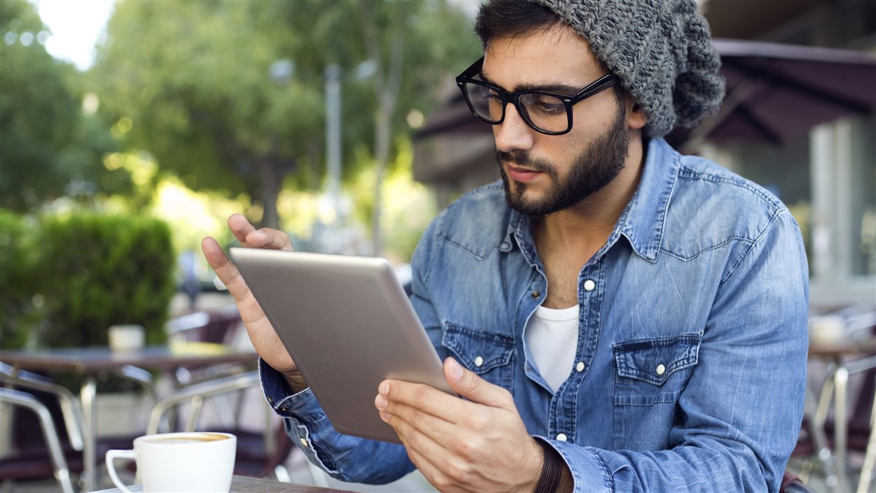 Un jeune homme avec sa tablette électronique dans un café Un jeune homme avec sa tablette électronique dans un café