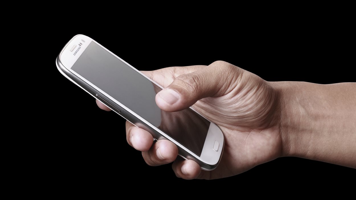 Un homme tient un téléphone intelligent. Un homme tient un téléphone intelligent.