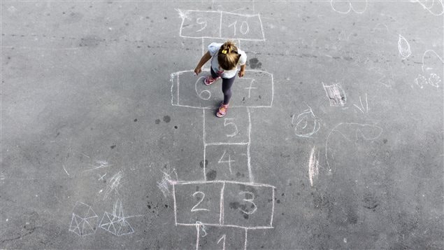 Une petite fille joue à la marelle dans une cour d'école Une petite fille joue à la marelle dans une cour d'école