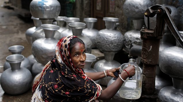 Une femme remplit une cruche d'eau à partir d'une pompe manuelle à Dhaka, au Bangladesh. Une femme remplit une cruche d'eau à partir d'une pompe manuelle à Dhaka, au Bangladesh.
