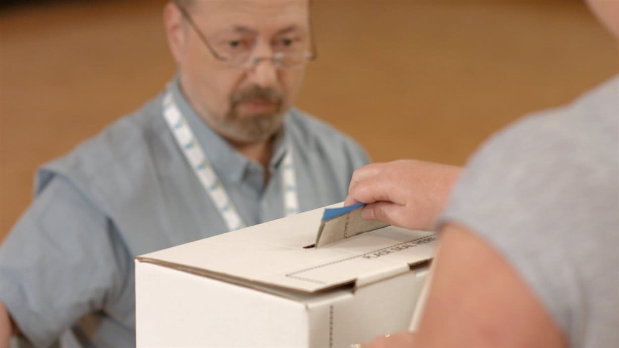 Un électeur dépose son bulletin de vote dans la boîte. Un électeur dépose son bulletin de vote dans la boîte.