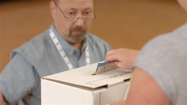 Un électeur dépose son bulletin de vote dans la boîte.