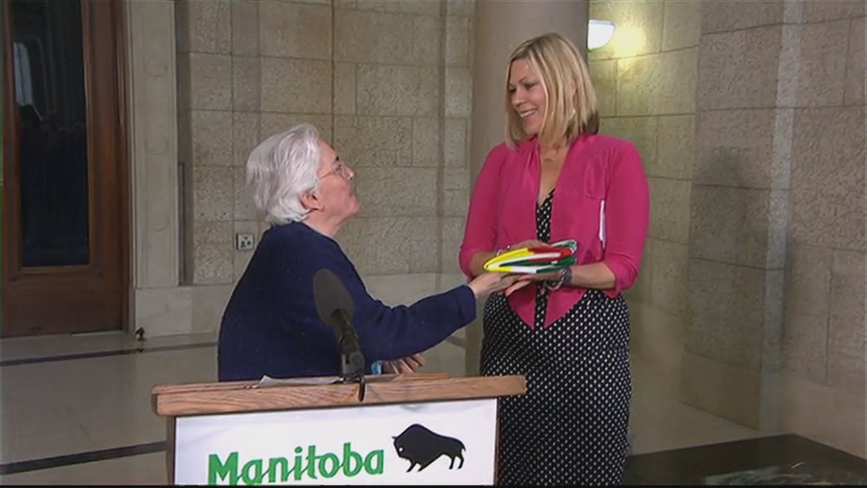 La présidente de la Société franco-Manitobaine Jacqueline Blay (à la gauche) remet un drapeau franco-manitobain à la ministre des Affaires francophones Rochelle Squires La présidente de la Société franco-Manitobaine Jacqueline Blay (à la gauche) remet un drapeau franco-manitobain à la ministre des Affaires francophones Rochelle Squires