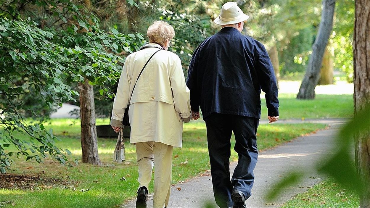 Un couple de personnes âgées se promènent dans un parc. 