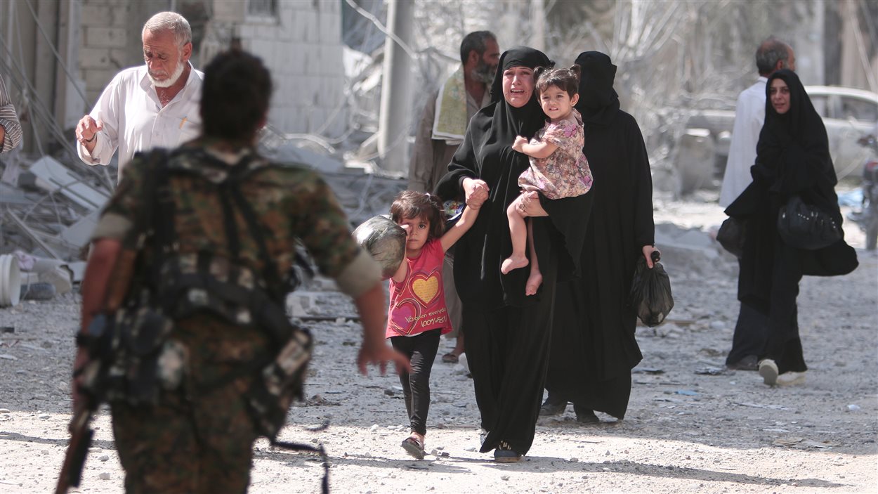 Un soldat rebelle se précipite pour aider des civils évacués d'un quartier de Manbij. Un soldat rebelle se précipite pour aider des civils évacués d'un quartier de Manbij.