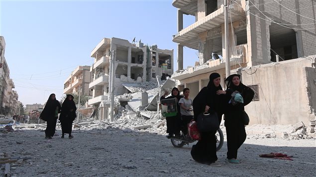 Des civils marchent dans les ruines de Manjib. Des civils marchent dans les ruines de Manjib.
