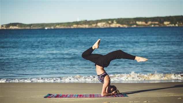 Une femme fait du yoga sur le bord de la mer
