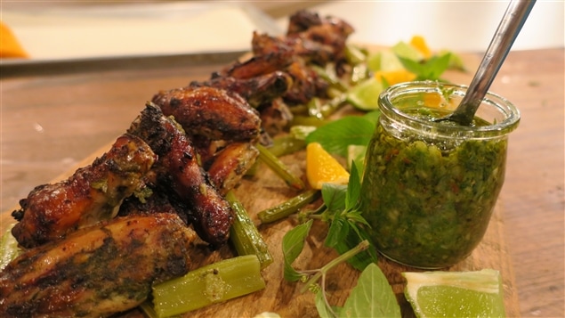 Gros plan d'une planche en bois avec des ailes de poulet et un pot de sauce verte. Gros plan d'une planche en bois avec des ailes de poulet et un pot de sauce verte.