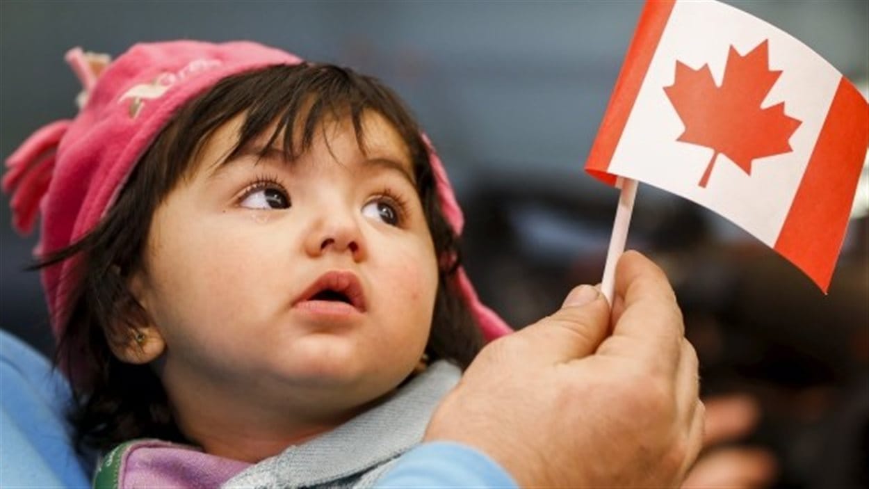Une jeune réfugiée syrienne regarde un petit drapeau du Canada. Une jeune réfugiée syrienne regarde un petit drapeau du Canada.