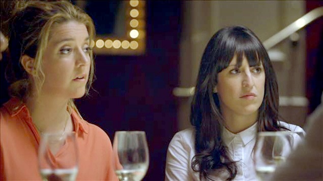 Les comédiennes Marie-Ève Perron et Anne-Élisabeth Bossé son attablées devant une coupe de vin et écoutent la conversation.