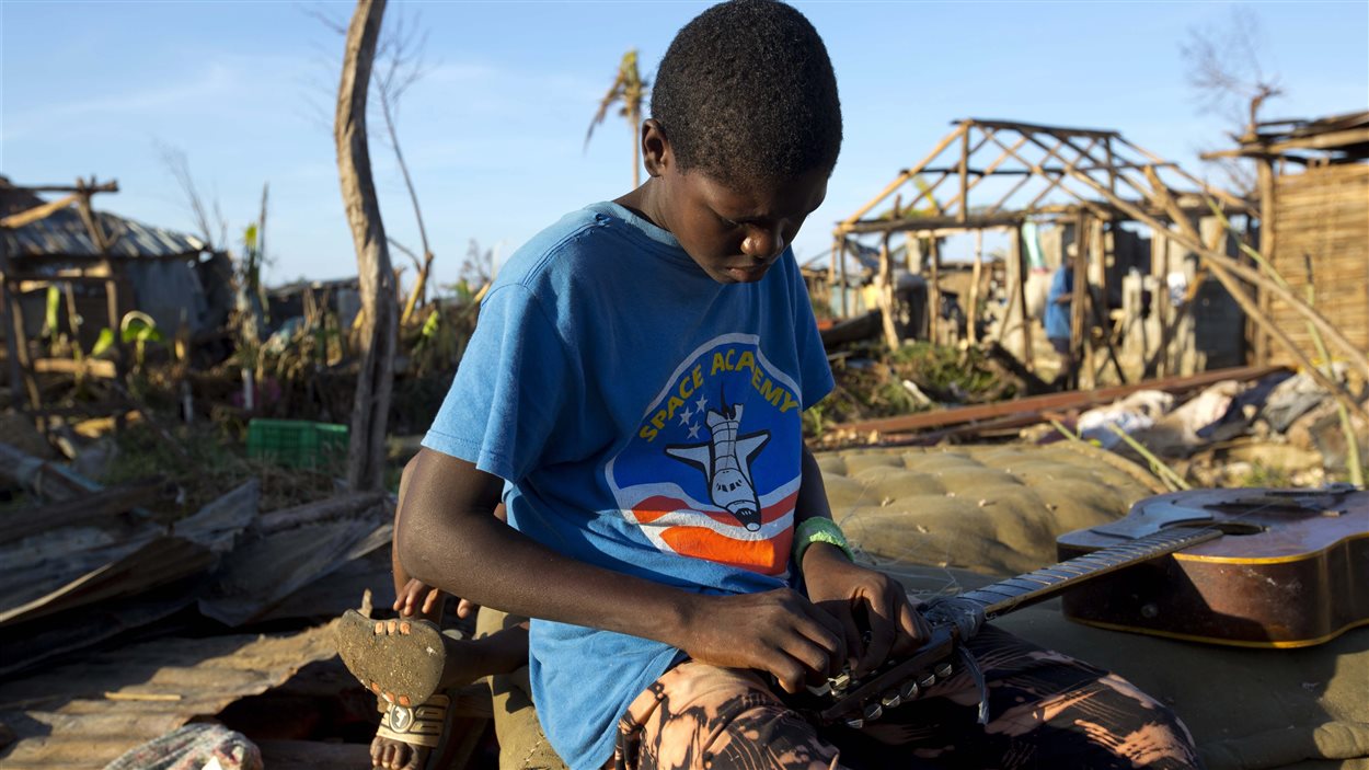 Un jeune garçon tente de réparer sa guitare à Hanse D’Hainault, en Haïti, le 11 octobre 2016, dans la dévastation causée par l’ouragan Matthew Un jeune garçon tente de réparer sa guitare à Hanse D’Hainault, en Haïti, le 11 octobre 2016, dans la dévastation causée par l’ouragan Matthew