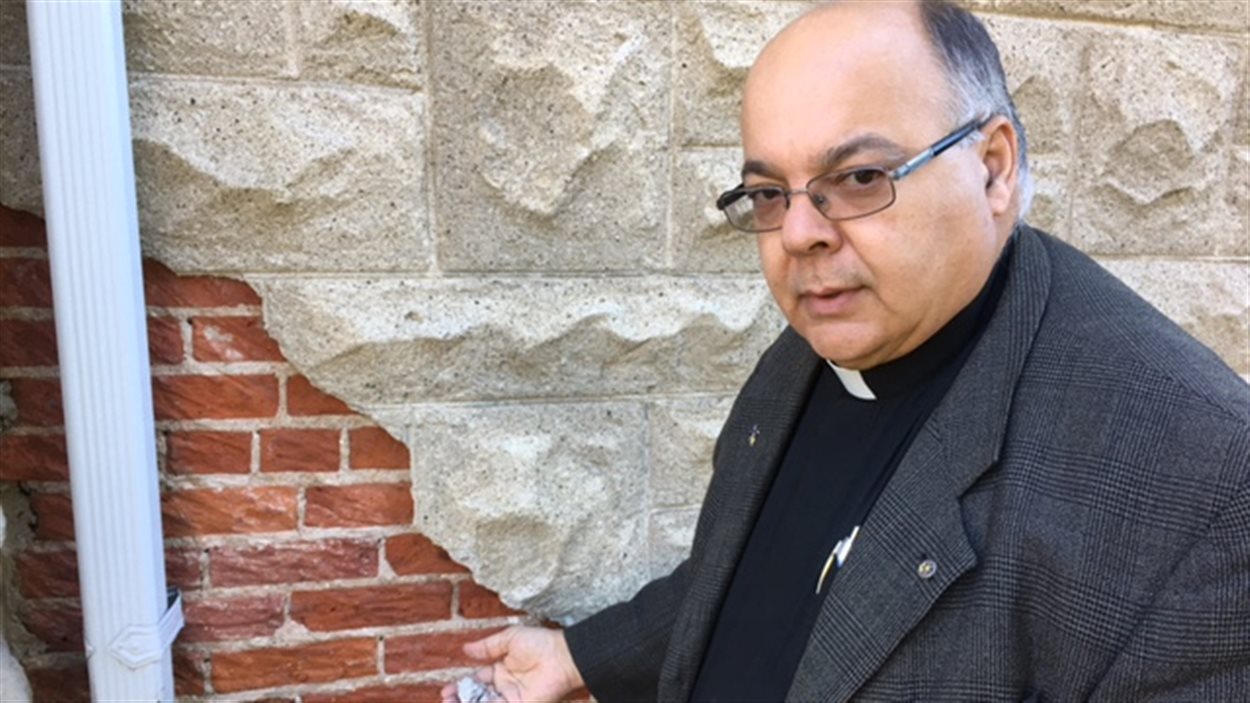 Le père Eugéne Roy montre les murs abîmés de l'église Le père Eugéne Roy montre les murs abîmés de l'église