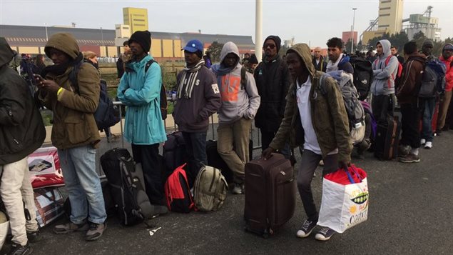Des migrants font la file pour monter dans les autobus. Des migrants font la file pour monter dans les autobus.