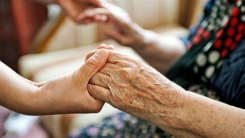 Un femme prend les mains d'une personne âgée Un femme prend les mains d'une personne âgée