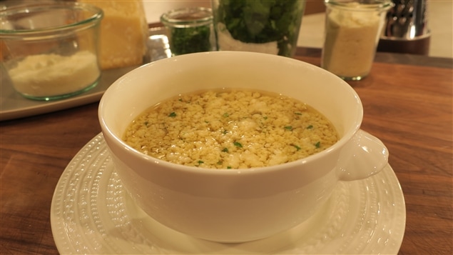 Une soupe stracciatella avec un parmesan dans un bol blanc