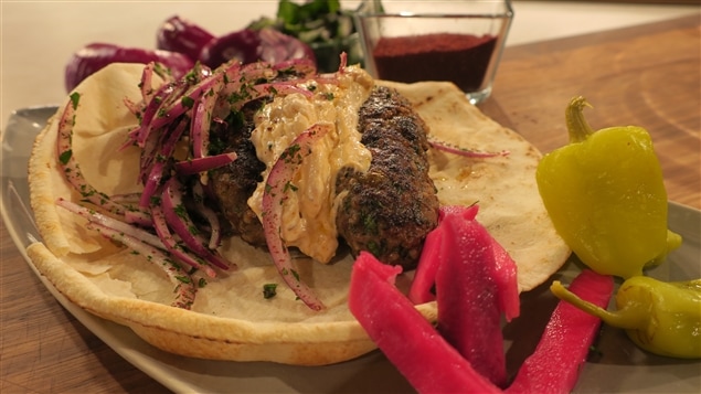 Un pain pita qui contient une boulette de viande, des oignons et de la sauce Un pain pita qui contient une boulette de viande, des oignons et de la sauce