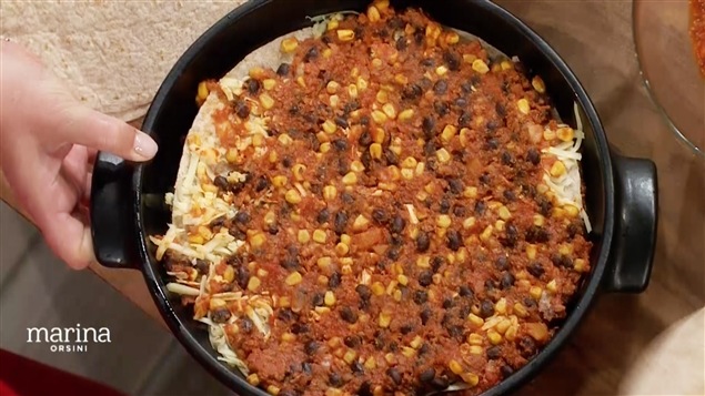 Une tortilla recouverte de fromage, de haricots rouges, de tomates et de maïs